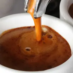 Caffè espresso che scende lentamente nella tazzina, creando una crema densa e invitante. Un piacere per gli occhi, se il caffè scende troppo piano, forse è ora di un caffè più forte.