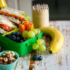 Gesunde Lunchbox mit Sandwiches, Beeren, Trauben, Karotten, Nüssen und Obst. Perfekt für kalorienarme Snacks unterwegs.
