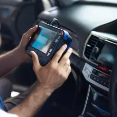 Mechanik trzymający w samochodzie urządzenie diagnostyczne do sterownika.