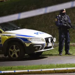 Polisbil och beväpnad polis, kanske Sandra Litzell, vid en avspärrning.