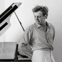 Maciej Musiał, z wykształceniem muzycznym, przy fortepianie, z nutami.