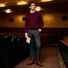 Uomo elegante in maglione bordeaux e pantaloni grigi, pronto per andare a teatro. Un esempio di come vestirsi per andare a teatro con stile.