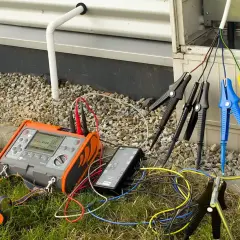Przyrząd do pomiaru rezystancji izolacji podłączony do przewodów instalacji elektrycznej.
