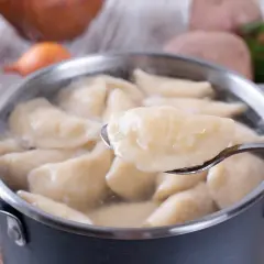 Gotowane pierogi w garnku, jeden na łyżce. Czy płukać pierogi po ugotowaniu? Zależy od przepisu!
