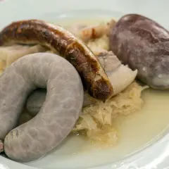 Eine bayerische Schlachtschüssel mit Blutwurst, Leberwurst und Bratwurst auf Sauerkraut.