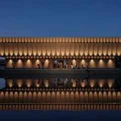 Elegant musik museum med träfasad och upplysta detaljer speglar sig i lugnt vatten.