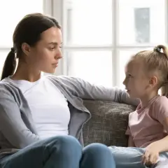 Kobieta i dziewczynka siedzą na kanapie i rozmawiają.