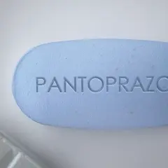 Ein hellblaues Pantoprazol-Tablett mit eingeprägtem Schriftzug. Manche Menschen nehmen Pantoprazol und Magnesium zusammen ein.