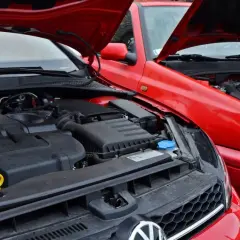 Dwa czerwone Volkswageny z otwartymi maskami, prezentujące swoje niezniszczalne silniki diesla TDI.
