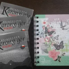 Trzy książeczki "Korony gór Polski" obok ozdobnego notesu w motyle i kwiaty. Idealne na górskie przygody!