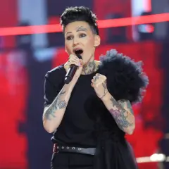 Agnieszka Chylińska śpiewa na scenie, przygotowując się do koncertów w 2026 roku. Jej charakterystyczny styl i tatuaże przyciągają wzrok.