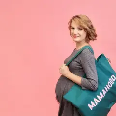Przyszła mama z torbą "Mamahood" zastanawia się, kiedy spakować torbę do szpitala.