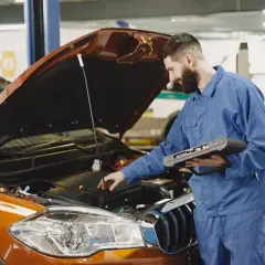Mechanik z komputerem diagnostycznym sprawdza silnik. Zastanawiasz się, jak długo trwa wymiana oleju? To zależy od modelu auta i doświadczenia mechanika.