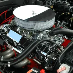 Błyszczący silnik V8 z chromowanymi elementami i czerwonymi przewodami zapłonowymi. Ten potężny motor, gotowy do pokonania wielu kw a km, to serce klasycznego muscle cara.