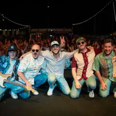 La tirock band festeggia con il pubblico, luci e chitarra elettrica sul palco.