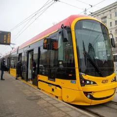 Nowy, żółto-czerwony 17 tramwaj warszawa z numerem 4201 stoi na przystanku. Pasażerowie wsiadają.