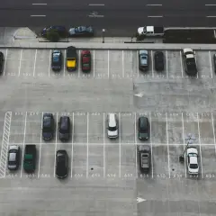 Widok z góry na parking. Samochód cofający na parkingu, kto ma pierwszeństwo? Wiele zaparkowanych aut.