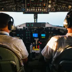Dwóch pilotów samolotu w słuchawkach na tle kokpitu.
