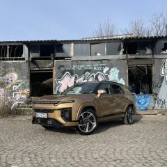 Złoty SsangYong Actyon na tle zniszczonego budynku z graffiti.