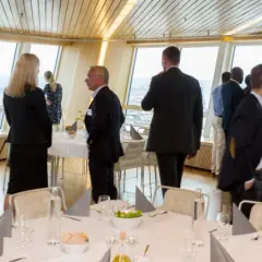 Människor i affärs kläder njuter av utsikten från en restaurang. En turning torso visning av staden.