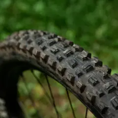 Close-up of a Maxxis Assegai tire, showing its aggressive tread pattern. This tire is ready for any trail.