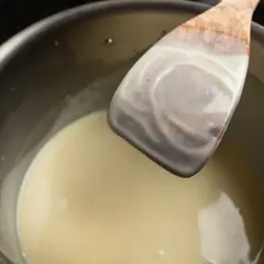 Cremige Masse wird mit einem Holzlöffel zur Rose abgezogen.