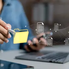 Main d'une personne utilisant un stylet pour interagir avec une icône de dossier jaune, symbolisant la digitalisation des processus et le flux de documents numériques.