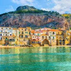 Case colorate affacciate sul mare di Cefalù, con la Rocca a dominare lo sfondo.