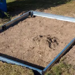 Metalowa rama na ziemi, gotowa na zrobienie fundamentu pod szklarnię.