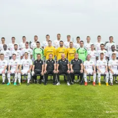 Radomiak Radom zawodnicy pozują do wspólnego zdjęcia. Drużyna w białych strojach, sztab szkoleniowy w czarnych.