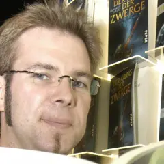 Markus Heitz, Autor von "Markus Heitz Die Zwerge Band 10", posiert vor seinen Büchern.