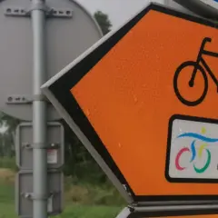 Pomarańczowy znak kierunkowy z rowerem i napisem "Wiślana Trasa Rowerowa" wskazuje drogę.