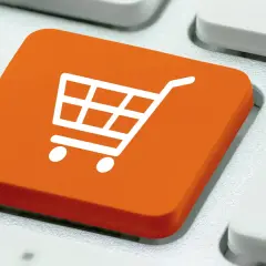 Pomarańczowy klawisz z ikoną koszyka na zakupy. To symbol e-commerce co to jest, czyli handlu elektronicznego.