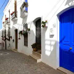 Calle empedrada con casas blancas y puertas azules vibrantes. Un lugar perfecto para descubrir qué hacer en Mojácar.