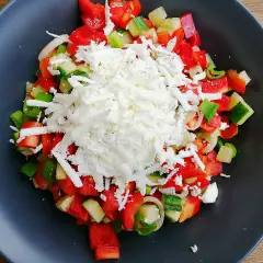 En fräsch sopska salata med hackad tomat, gurka, paprika och lök, toppad med smulad fetaost.