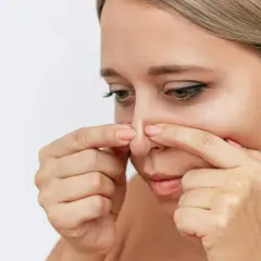 En kvinna undersöker sin näsa, där en pormask som fylls på syns tydligt.