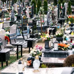 Ławki na cmentarzu, przygotowane na wizytę bliskich. Wiele zniczy i kwiatów świadczy o pamięci.