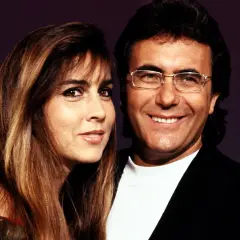 Al Bano i Romina Power, uśmiechnięci, pozują do zdjęcia. Ona ma długie, brązowe włosy, on okulary.