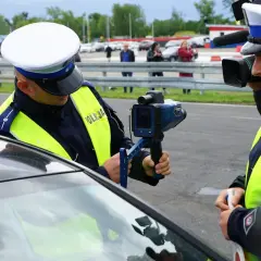 Policjant mierzy prędkość, grozi zabrane prawo jazdy za prędkość. Inny funkcjonariusz filmuje akcję.