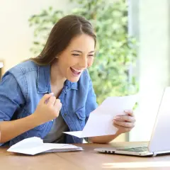 Kobieta cieszy się z pozytywnej odpowiedzi na temat, jak negocjować podwyżkę. Sukces w pracy!