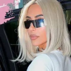 Frau mit platinblonden Haaren und futuristischen Sonnenbrillen steigt aus einem Auto.