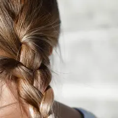 Gładki warkocz z blond włosów, który może być efektem stosowania metod na to, jak zmniejszyć porowatość włosów.
