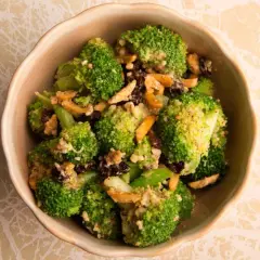 Ensalada de brócoli fresca con pasas y nueces, servida en un cuenco de cerámica.