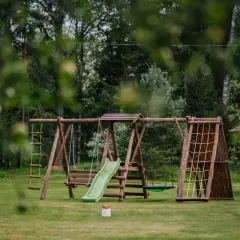 Drewniany plac zabaw z huśtawkami, zjeżdżalnią i ścianką wspinaczkową. Idealne miejsce, by dowiedzieć się, jak zrobić małpi gaj w ogrodzie.
