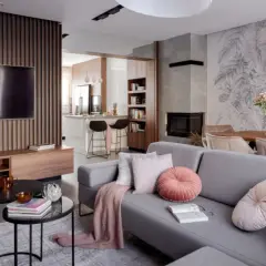 Nowoczesny salon z szarą sofą, kominkiem i otwartą kuchnią. Galeria wnętrz zachwyca detalami.
