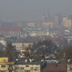 Mglisty widok Krakowa z wieżą kościelną i zamkiem. Warto wiedzieć, jak chronić się przed zanieczyszczeniami powietrza w takich warunkach.