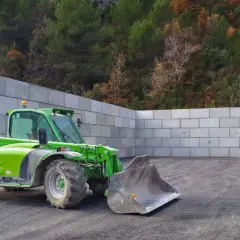 Chargeuse verte dans un espace clos de murs en blocs de béton, prêt pour le silo ensilage.