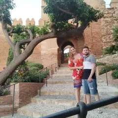 Pareja posando en escalinatas de piedra con un árbol retorcido y murallas de cañarete Almería de fondo.