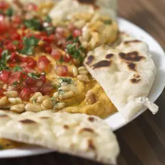 Chlebek naan z czym podawać? Pyszny hummus z granatem, orzeszkami pinii i natką pietruszki, idealny do maczania.