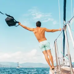 Uomo con zaino in barca a vela, un esempio di come vestirsi in barca a vela: costume e libertà.